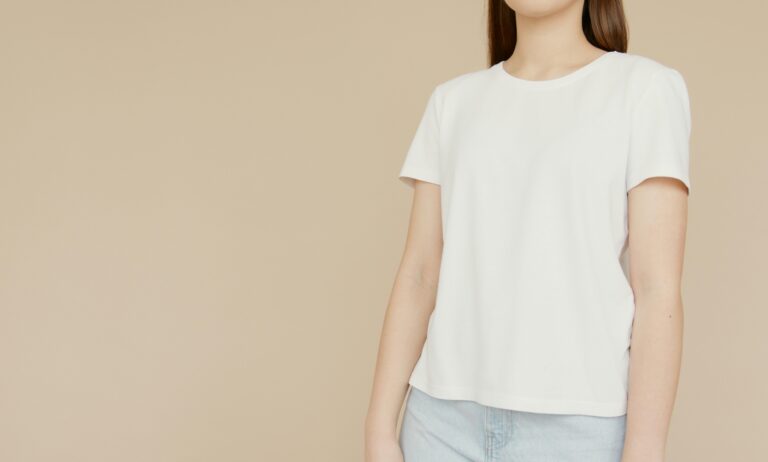Minimalist photo of a woman in a white t-shirt with a beige background, perfect for fashion or lifestyle themes.